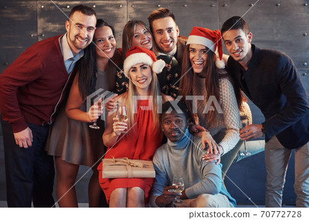 New Year is coming! Group of cheerful young multiethnic people in Santa hats on the party, posing emotional lifestyle people concept New Year is coming! Group of cheerful young multiethnic people in Santa hats on the party, posing emotional lifestyle people concept 70772728