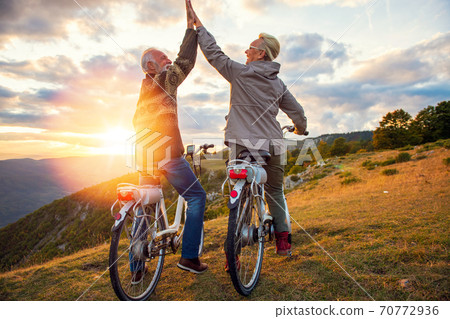 Active Senior Couple celebrating success on beautiful sunset. 70772936