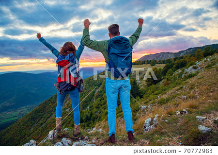 Couple on Top of a Mountain Shaking Raised Hands 70772983