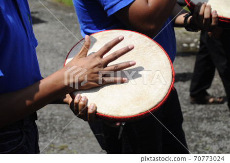 KUALA LUMPUR, MALAYSIA -MARCH 2, 2019: Boy plays kompang during Malay traditional wedding ceremony. They will sing songs together while playing the kompang.Kompang is a Malay traditional drums. KUALA LUMPUR, MALAYSIA -MARCH 2, 2019: Boy plays kompang during Malay traditional wedding ceremony. They will sing songs together while playing the kompang.Kompang is a Malay traditional drums. 70773024