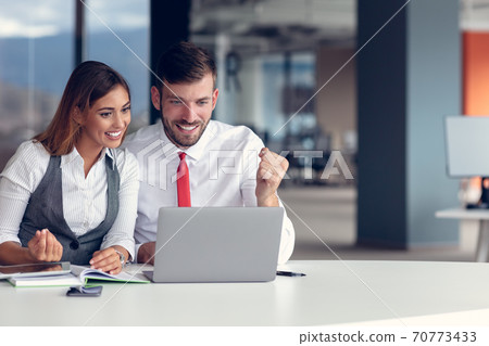 Coworkers celebrating success in modern office using laptop computer Coworkers celebrating success in modern office using laptop computer 70773433