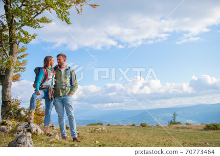 Happy couple hiking and enjoying a valley view Happy couple hiking and enjoying a valley view 70773464