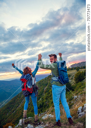 Couple on Top of a Mountain Shaking Raised Hands 70773473