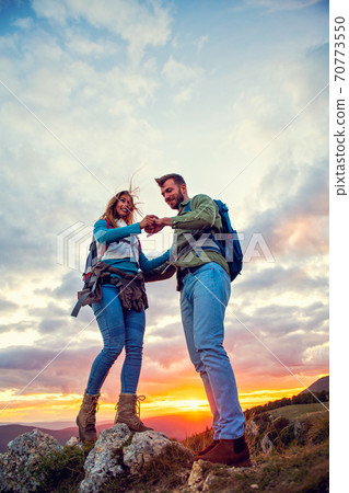 Couple on Top of a Mountain Shaking Raised Hands 70773550