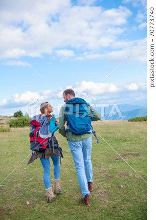 Happy couple hiking and enjoying a valley view. Photo taken from back. 70773740
