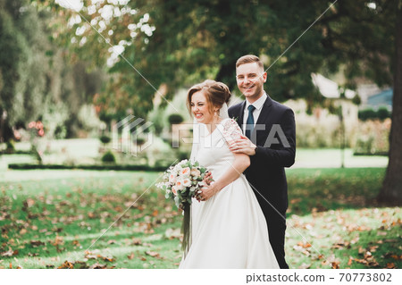 Beautiful romantic wedding couple of newlyweds hugging in park Beautiful romantic wedding couple of newlyweds hugging in park 70773802