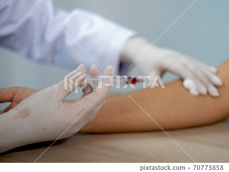 Doctors hands use syringe for collecting blood samples to analyze the cause of the illness 70773858