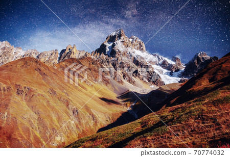 Fantastic starry sky. Autumn landscape and snow-capped peaks. Main Caucasian Ridge. Mountain View from Mount Ushba Meyer, Georgia. Europe 70774032