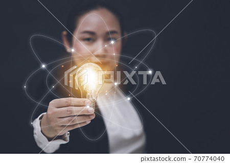 Business Asian woman Holding Illuminated Light Bulb with innovative and creativity are keys to success,innovation and inspiration,ideas and inspiration. concept Business Asian woman Holding Illuminated Light Bulb with innovative and creativity are keys to success,innovation and inspiration,ideas and inspiration. concept 70774040