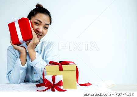 Woman in a blue shirt holding a red gift box tied with a red ribbon present for the festival of giving special holidays like Christmas, Valentine's Day 70774137