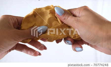Female hands are molded from gold plasticine, developing activities for children. 70774248