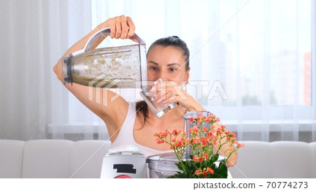 Close-up of woman with blender pouring detox cocktail Close-up of woman with blender pouring detox cocktail 70774273