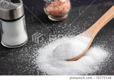 White sea salt for cooking food in Small glass bottles and wooden spoons on a stone tray background. White sea salt for cooking food in Small glass bottles and wooden spoons on a stone tray background. 70775549