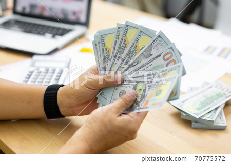 Man counting dollar banknotes on desk. concept of salary,tax and income Man counting dollar banknotes on desk. concept of salary,tax and income 70775572