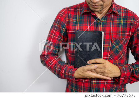 Believer man holding bible book on chest Believer man holding bible book on chest 70775573