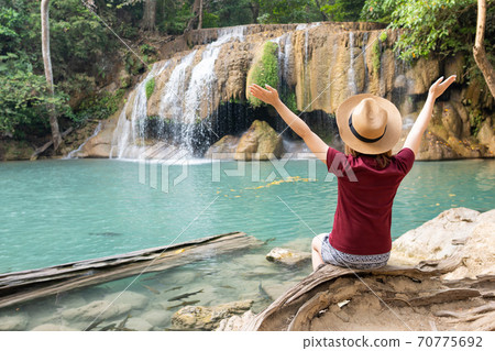 Rear view of young woman traveling in Erawan waterfall in Kanchanaburi Thailand Rear view of young woman traveling in Erawan waterfall in Kanchanaburi Thailand 70775692