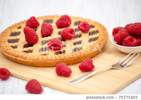 Dessert Raspberry Pie cake with strawberry or Fruit in a round bread for Break time or a party shot at the top view and copy space on a white wooden table. 70775805