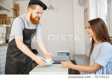 Coffee Business Concept - Waiter or bartender serving hot coffee and talking with caucasian beautiful lady in blue dress at Coffee shop. 70776222