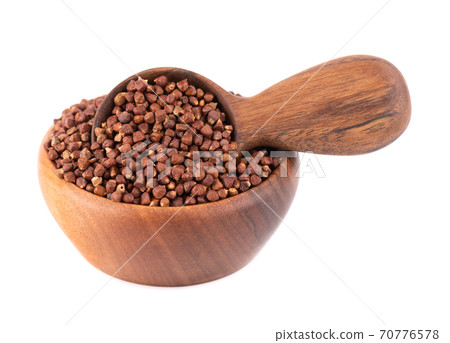 Guinea pepper grains in wooden bowl and spoon, isolated on white background. Melegeta, alligator pepper or mahlab. Grains of paradise. 70776578