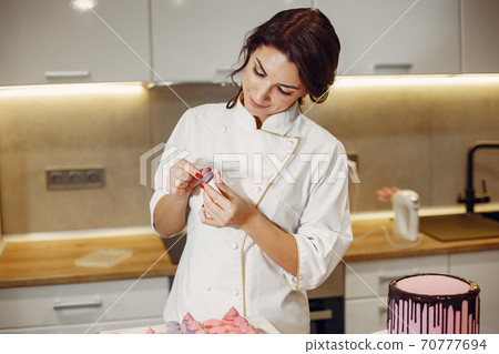 Confectioner in a uniform decorates the macaroni 70777694