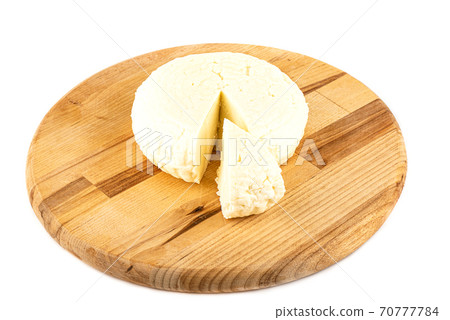 Round soft cheese on a wooden cutting board. 70777784