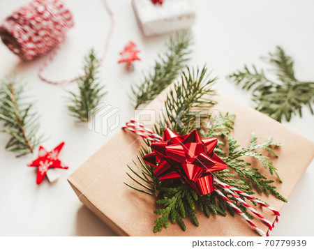 Christmas DIY presents wrapped in craft paper with fir tree branches and red bow. Decorations on New Year gifts. Festive background. Winter holiday spirit. Christmas DIY presents wrapped in craft paper with fir tree branches and red bow. Decorations on New Year gifts. Festive background. Winter holiday spirit. 70779939