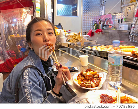 Young woman eating crunchy korean fried chicken street food in Seoul, South Korea Young woman eating crunchy korean fried chicken street food in Seoul, South Korea 70782686