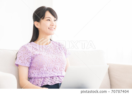 觀看一台便攜式計算機的婦女在屋子裡 觀看一台便攜式計算機的婦女在屋子裡 70787404