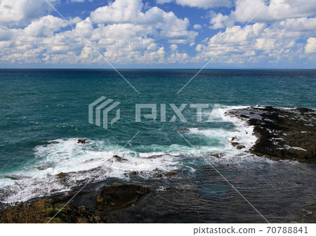 White clouds float in the blue sky, azure sea and coastal scenery where white waves hit the reef 70788841