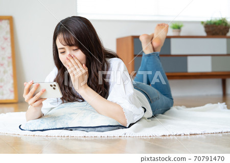 A young woman crying while watching a video while lying in the living room A young woman crying while watching a video while lying in the living room 70791470