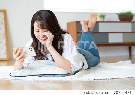 一名年輕女子躺在客廳裡一邊看視頻一邊哭 一名年輕女子躺在客廳裡一邊看視頻一邊哭 70791471
