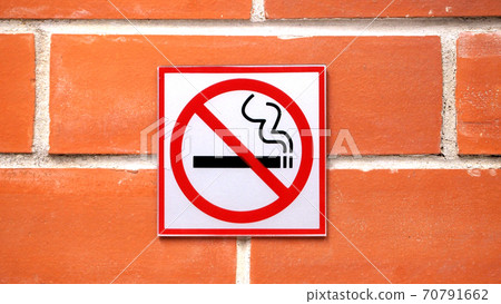 Sign hangs on a brick wall warning that smoking is not permitted in the area Sign hangs on a brick wall warning that smoking is not permitted in the area 70791662
