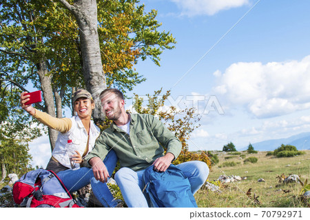 Young couple drinking water while resting on the rock during the travel in the mountains 70792971