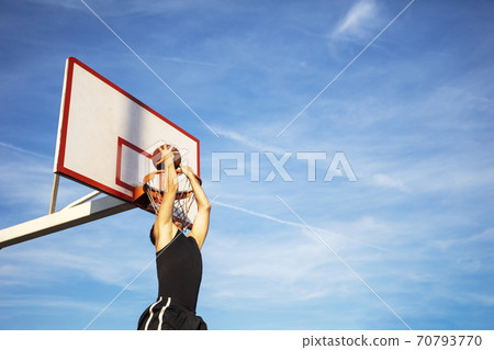 Young man jumping and making a fantastic slam dunk playing streetball, basketball. Urban authentic. 70793770