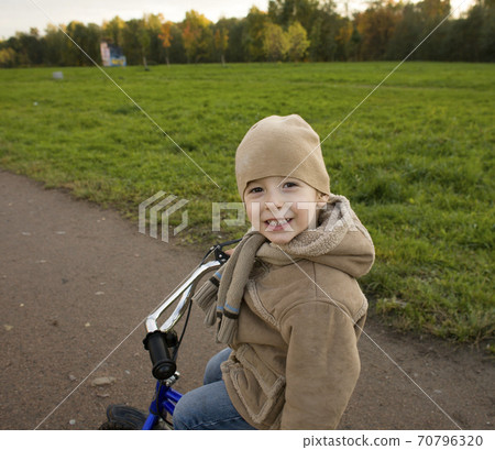 little cute real boy on bicycle emotional smiling close up outside in green amusement park little cute real boy on bicycle emotional smiling close up outside in green amusement park 70796320