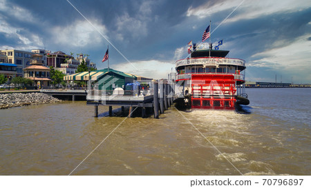 Port of New Orleans in Louisiana USA day light view showing The steamboat Natchez on Mississippi River with American flags, Skylines and clouds in the sky in background. 70796897