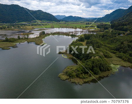 Aerial view on the upper ends of Ossiacher Lake in Carinthia, Austria with its moor and marshlands on a summer day with great cloudscape 70797376