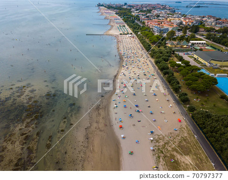 Aerial view of unidentifiable people enjoying summer at the beach of Grado in the province of Gorizia at the Northern Adriatic Sea 70797377
