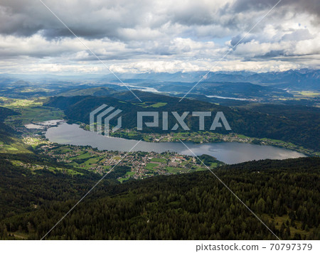 Aerial drone view on Ossiacher Lake in Carinthia, Austria on a summer day with great cloudscape and Lake Woerthersee in the background 70797379