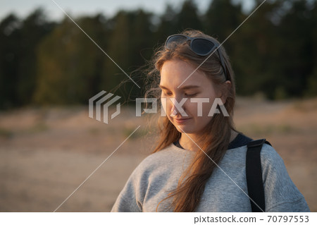 Portrait of girl in warm pullover walking on a beach during sunset 70797553