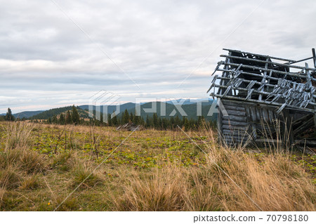 Stack of wooden planks of old shed up in mountains with cloudy sky and dried grass around. 70798180