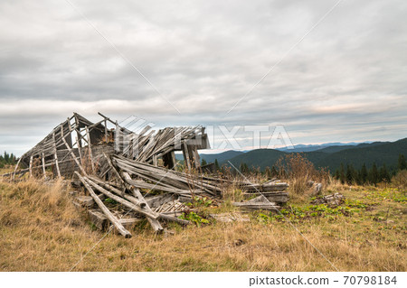 A pile of gray wooden planks of old ruined tourist shelter in the mountains. A pile of gray wooden planks of old ruined tourist shelter in the mountains. 70798184