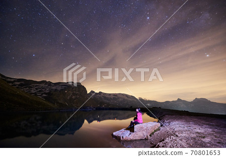 Scenery of night mountains, woman sitting near lake. Scenery of night mountains, woman sitting near lake. 70801653