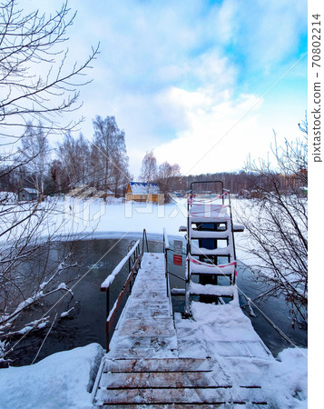Stairs for swimming in an ice hole on the lake after a sauna on a cold day. Stairs for swimming in an ice hole on the lake after a sauna on a cold day. 70802214