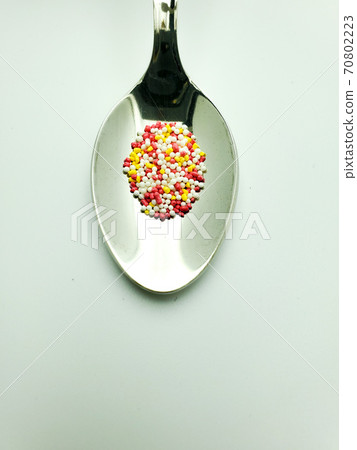 granules from capsules in a teaspoon on a white background 70802223