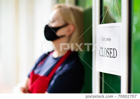 Owner hanging closed sign board on shop entrance. Owner hanging closed sign board on shop entrance. 70802707