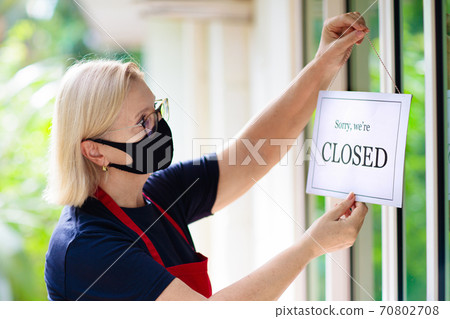 Owner hanging closed sign board on shop entrance. Owner hanging closed sign board on shop entrance. 70802708