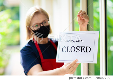 Owner hanging closed sign board on shop entrance. Owner hanging closed sign board on shop entrance. 70802709