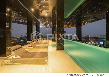 Empty luxury swimming pool in hotel, condominium apartment, or resort. Lights illuminated at night time. Interior and architecture design decoration. 70803643