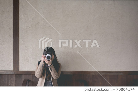 A woman taking a picture with a single-lens reflex camera 70804174